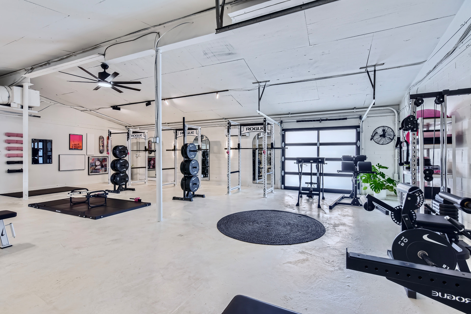Inside the Axiom Fitness Studio gym — bright white space with squat racks, benches, and black weight plates